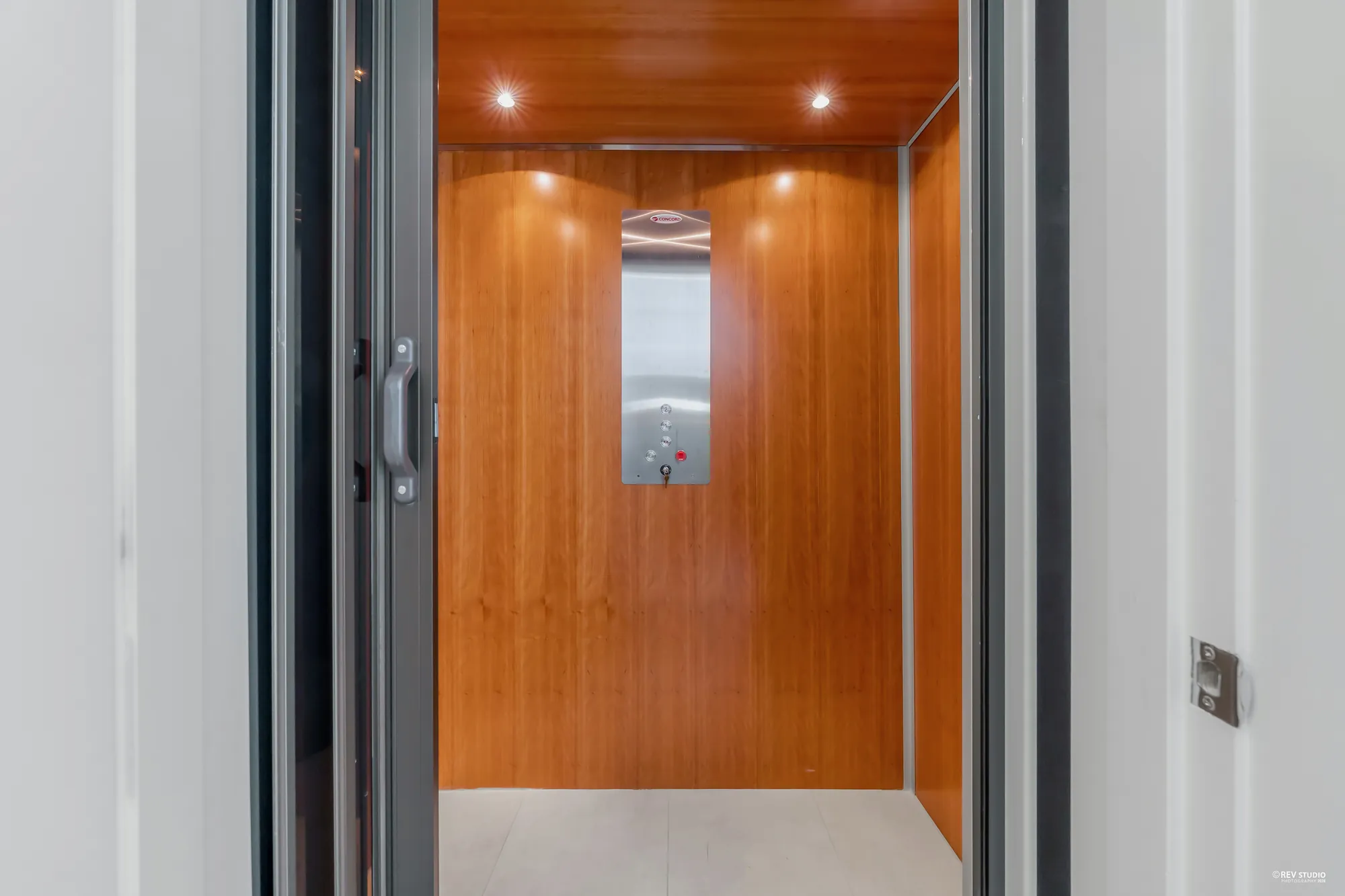 The private elevator: a cab lined in cherry-coloured wood with a stainless control panel, its door open
