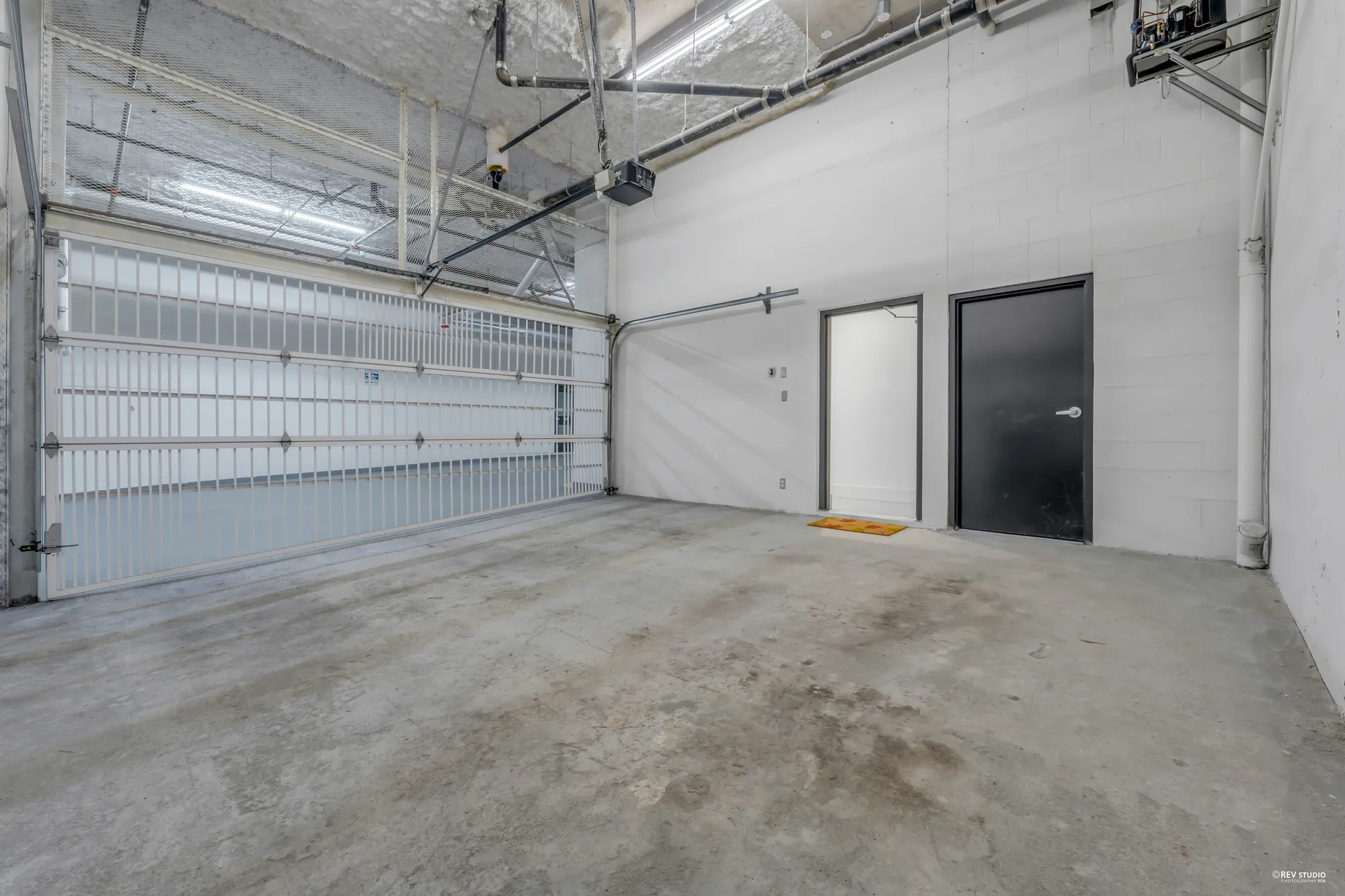 The double garage: a wide sectional door, a concrete floor and two doors in the back wall
