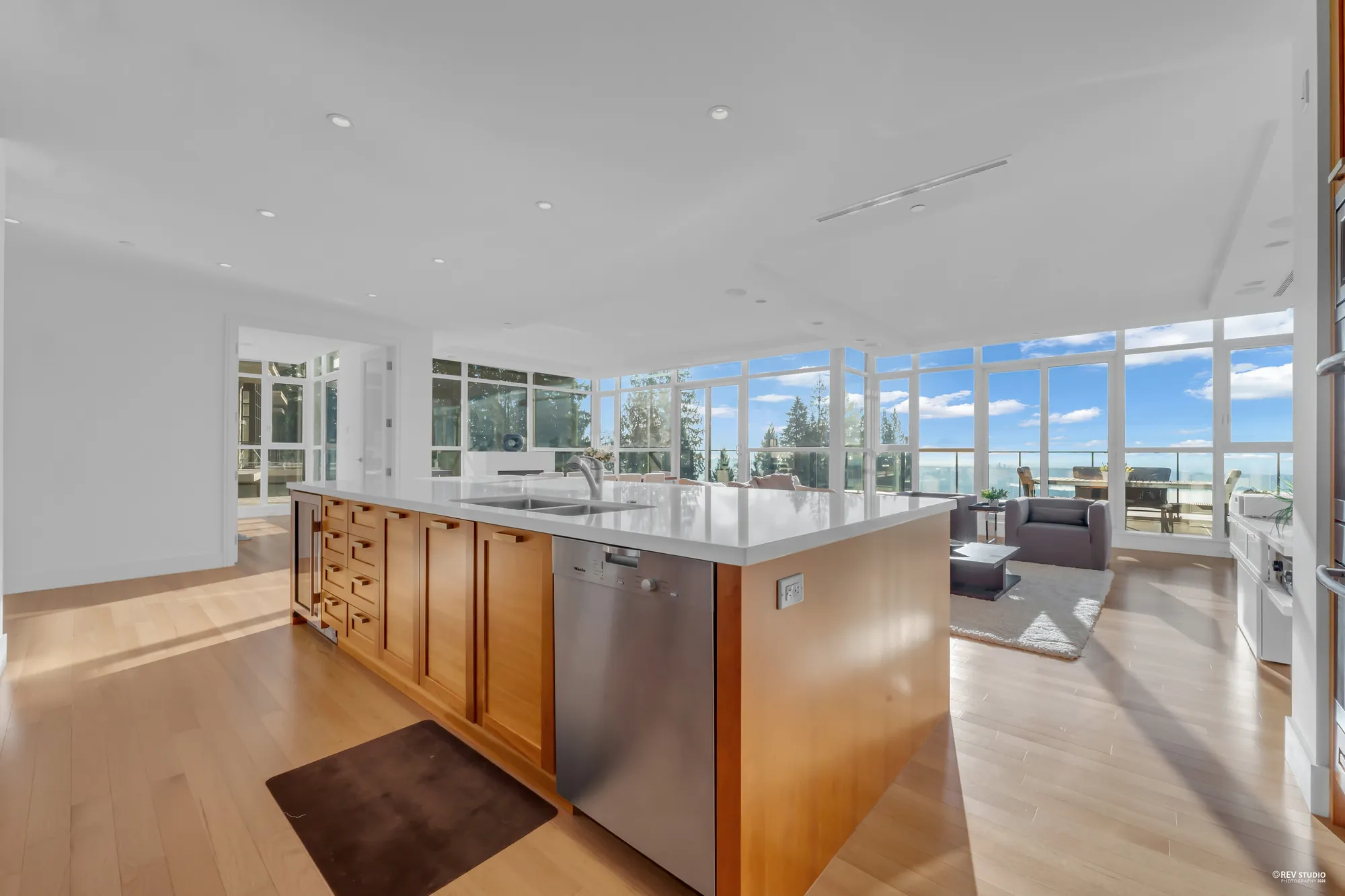 The island with its sink and a stainless dishwasher, the dining area and the windows beyond