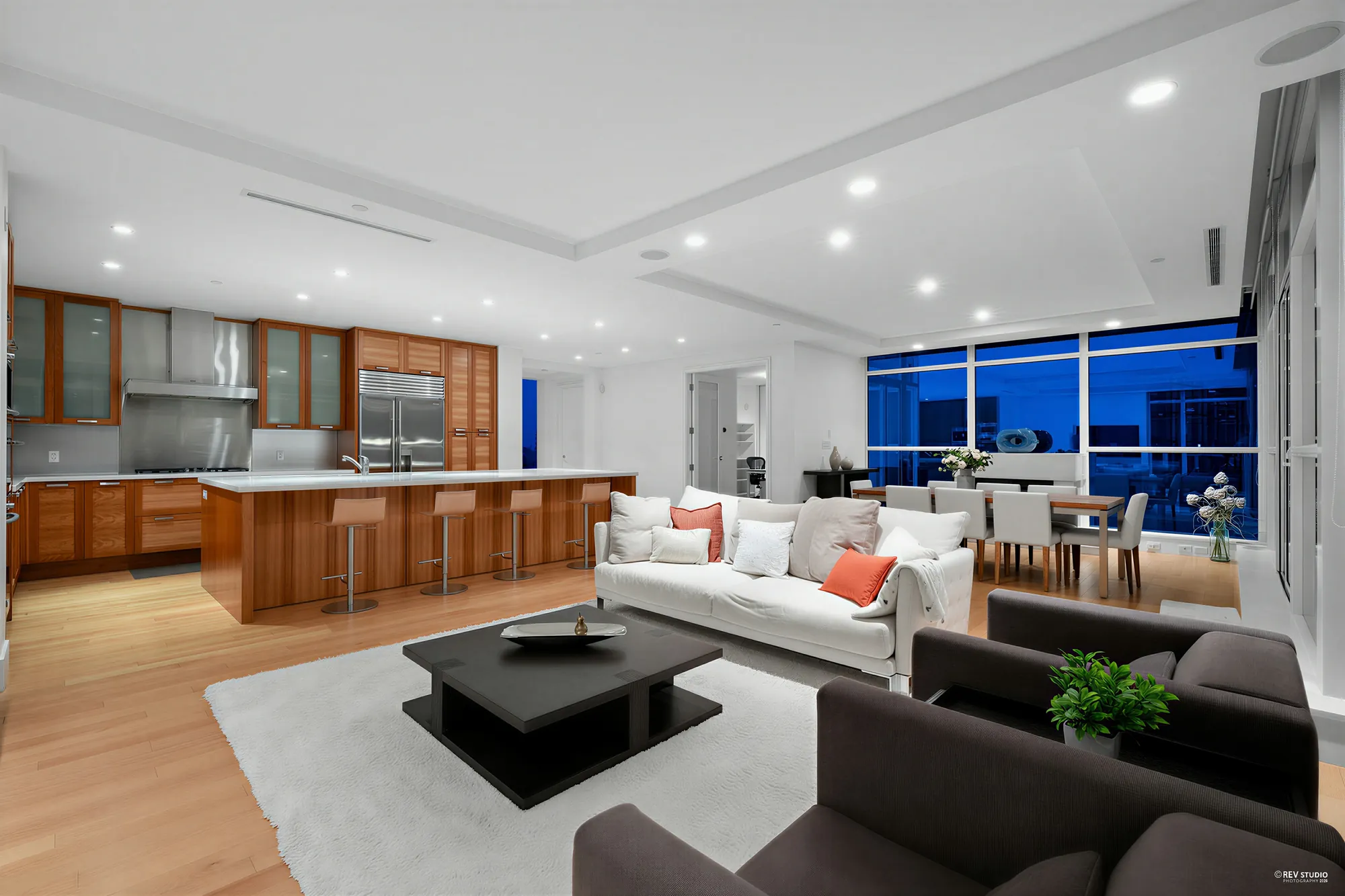 The same view toward the kitchen at dusk, the island and the cabinets lit