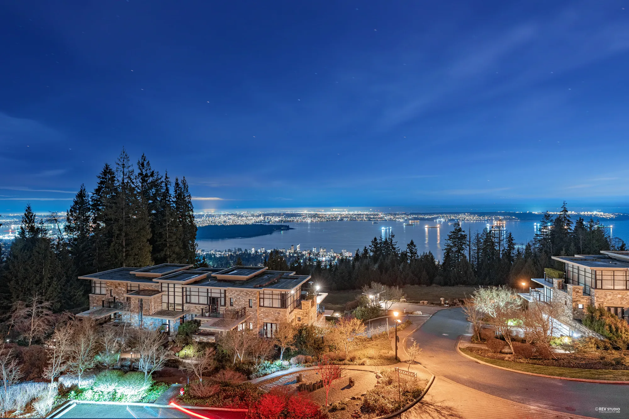 The same view at dusk: the garden lights of the complex below, the water and the lit shore beyond